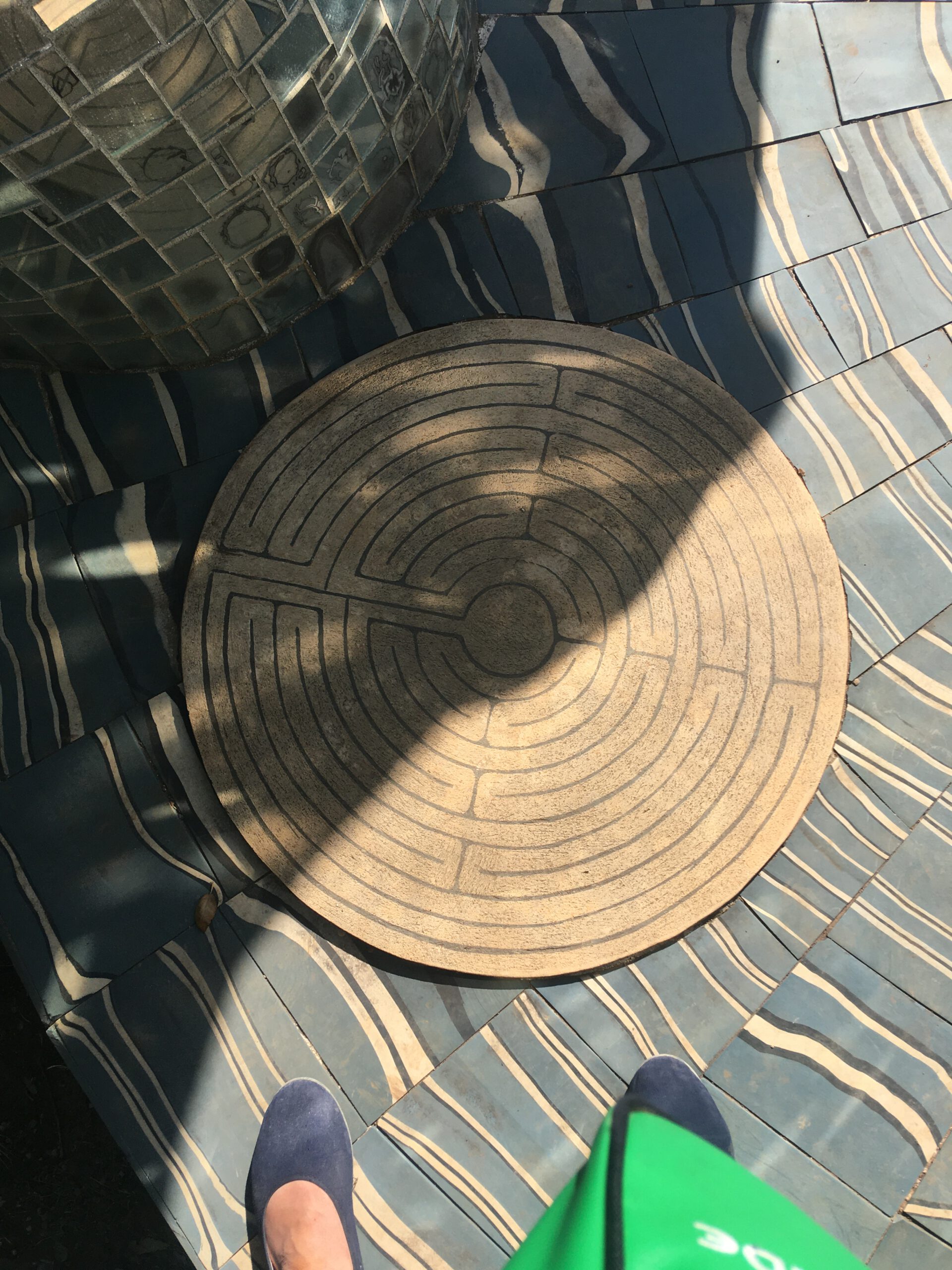 Foto zeigt zwei Füße in Sommerschuhen, die vor einem kleinen Labyrinth stehen (Foto S.Jordan 2020 Tarotgarten Capalbio, Toscana)